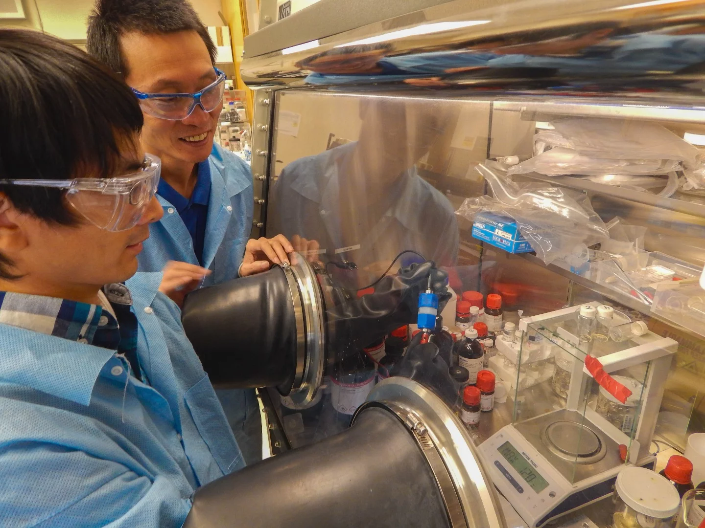 From left, LLNL postdoc Jianchao Ye works on a lithium ion battery, while Morris Wang looks on