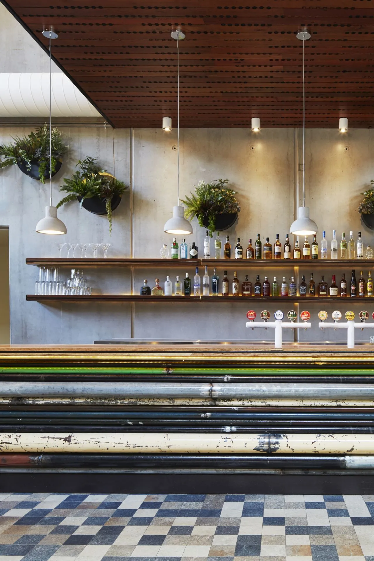 The service bar features an array of salvaged colorful piping and elegant hanging concrete cast lamps