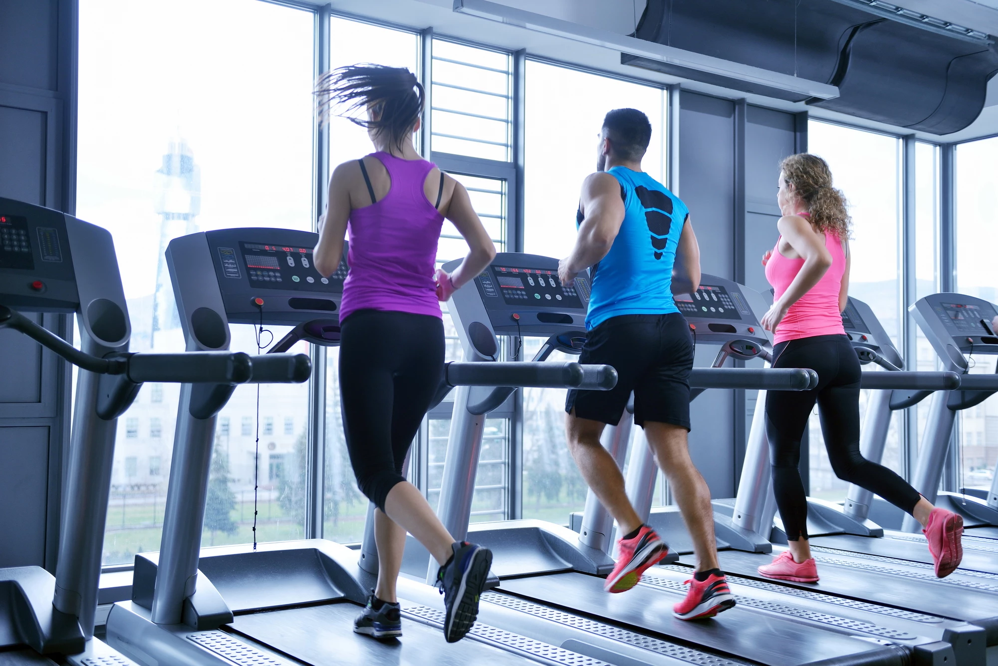 group of young people running on treadmills in modern sport gym