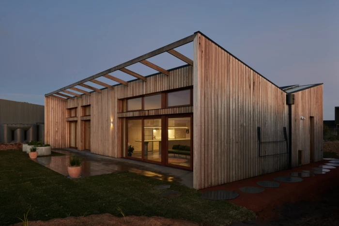 The home features a FSC hardwood clad exterior and a butterfly-shaped roof