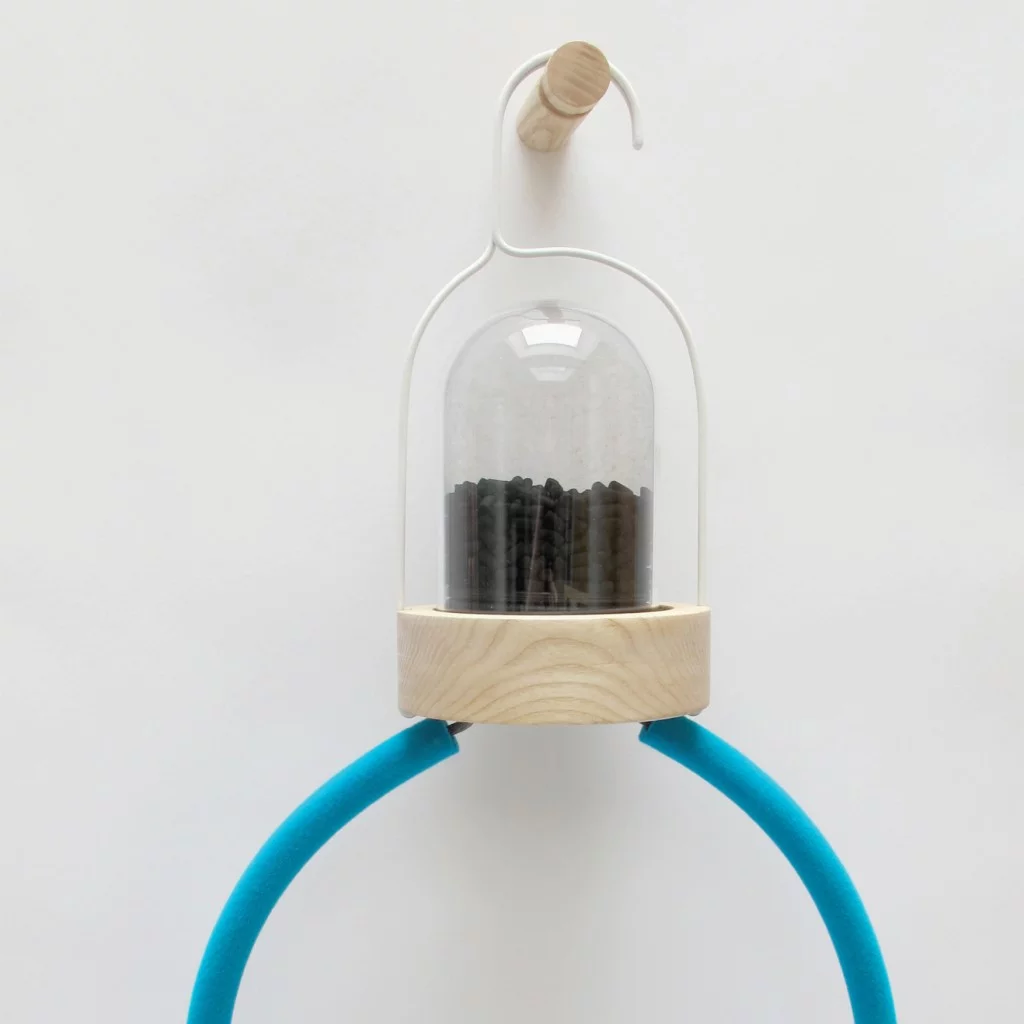 A close-up of the glass chamber and its activated charcoal contents sitting atop the Bye Bye Laundry clothes hangers