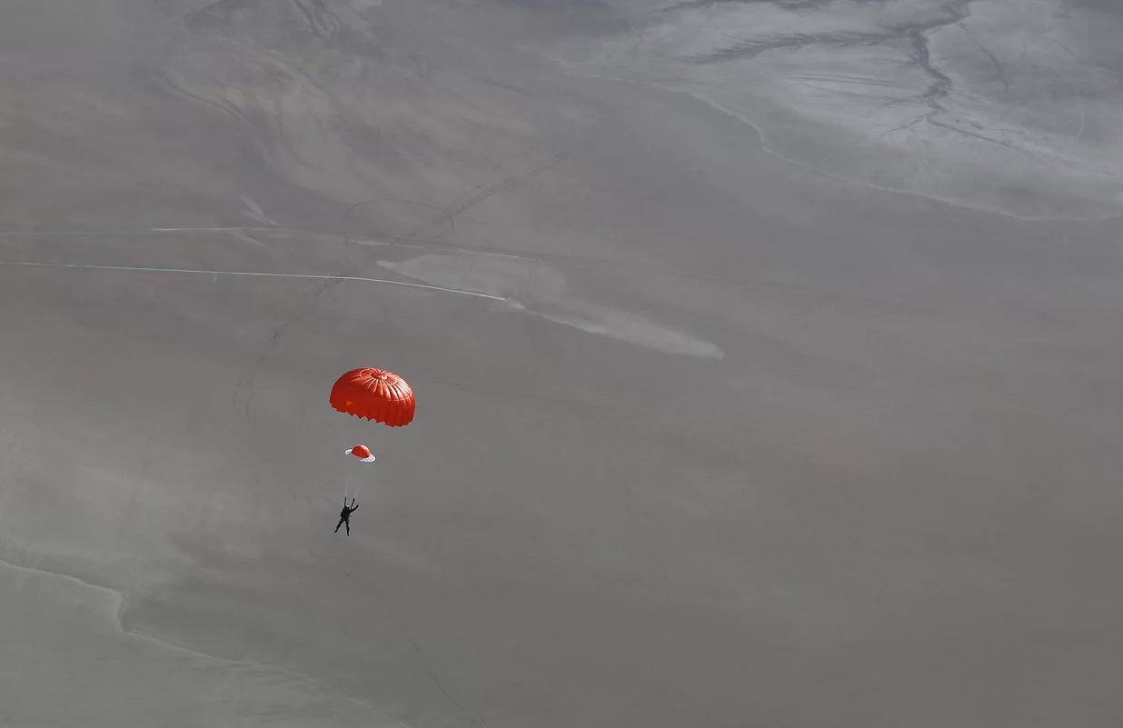 Pilot Pete Siebold as he parachutes safely down to earth after the accident, with his arm up in the air to show everybody that he is alive and well