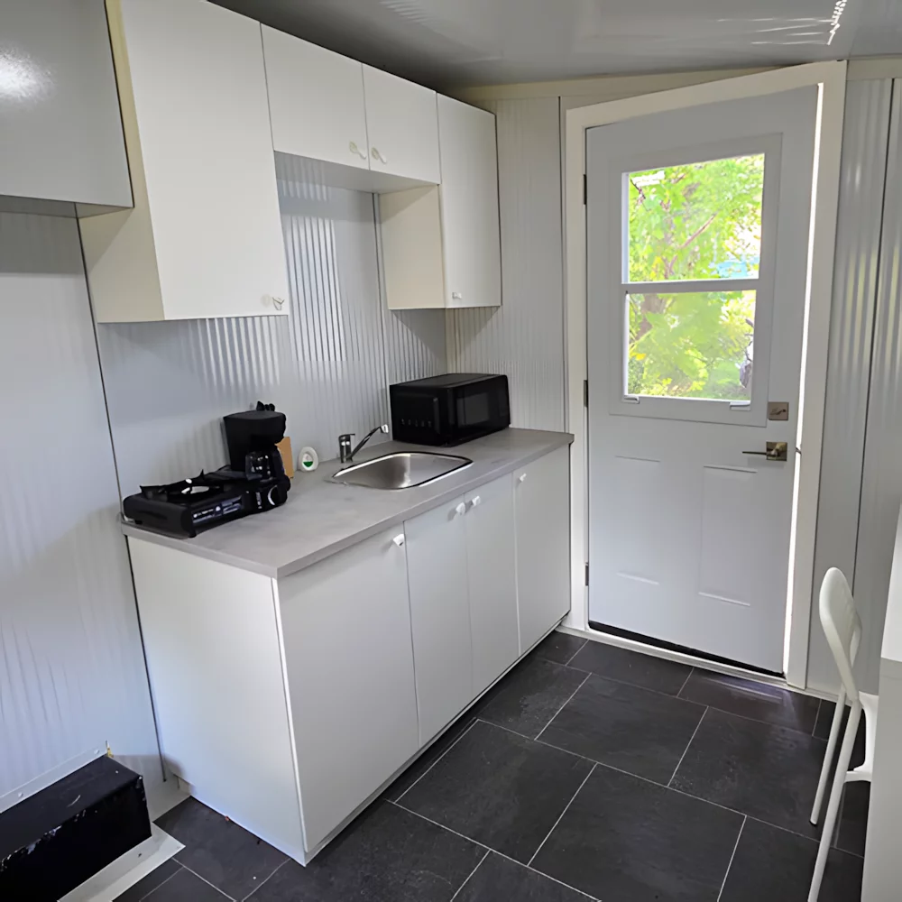 The larger tiny house includes a kitchenette and a desk area