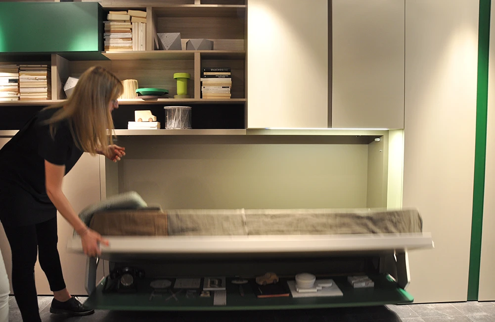 As the user pulls the bed down from the wall, the table sits underneath the bed base with no needs to displace objects from the top
