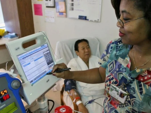 Nurse Agatha Ekeh, right, updates patient Charles Khim's medical record using Motion Computing's C5, the first product based on Intel's mobile clinical assistant platform, Tuesday, Feb. 20, 2007, at UCSF Medical Center in San Francisco.