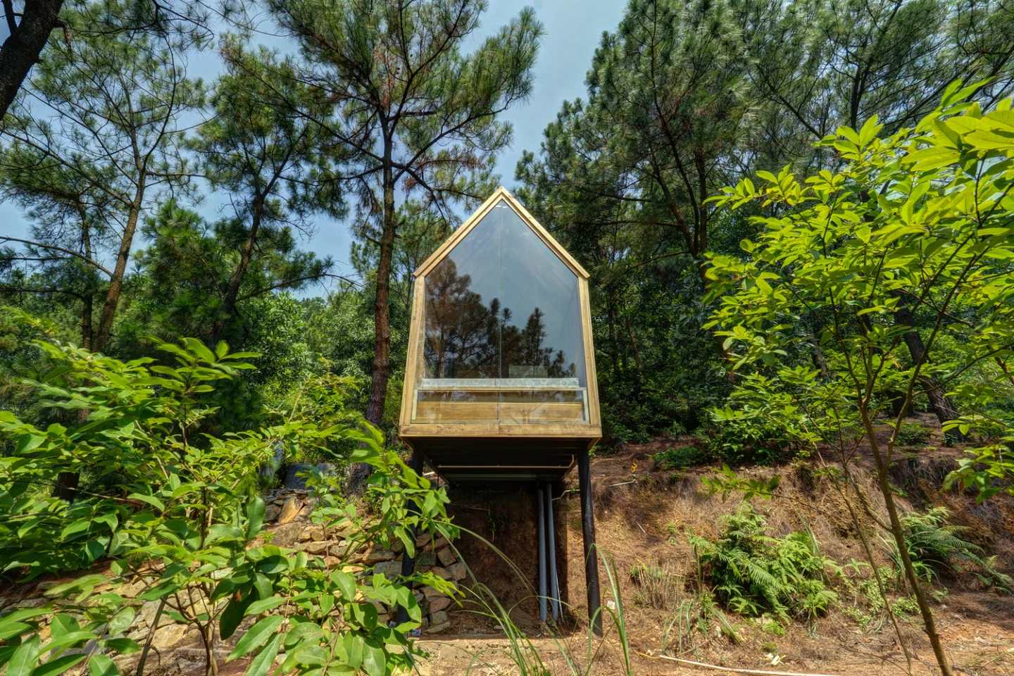 The cabin features a large floor-to-ceiling glass wall at the front ofthe home, capitalizing on its surrounding views and lush setting