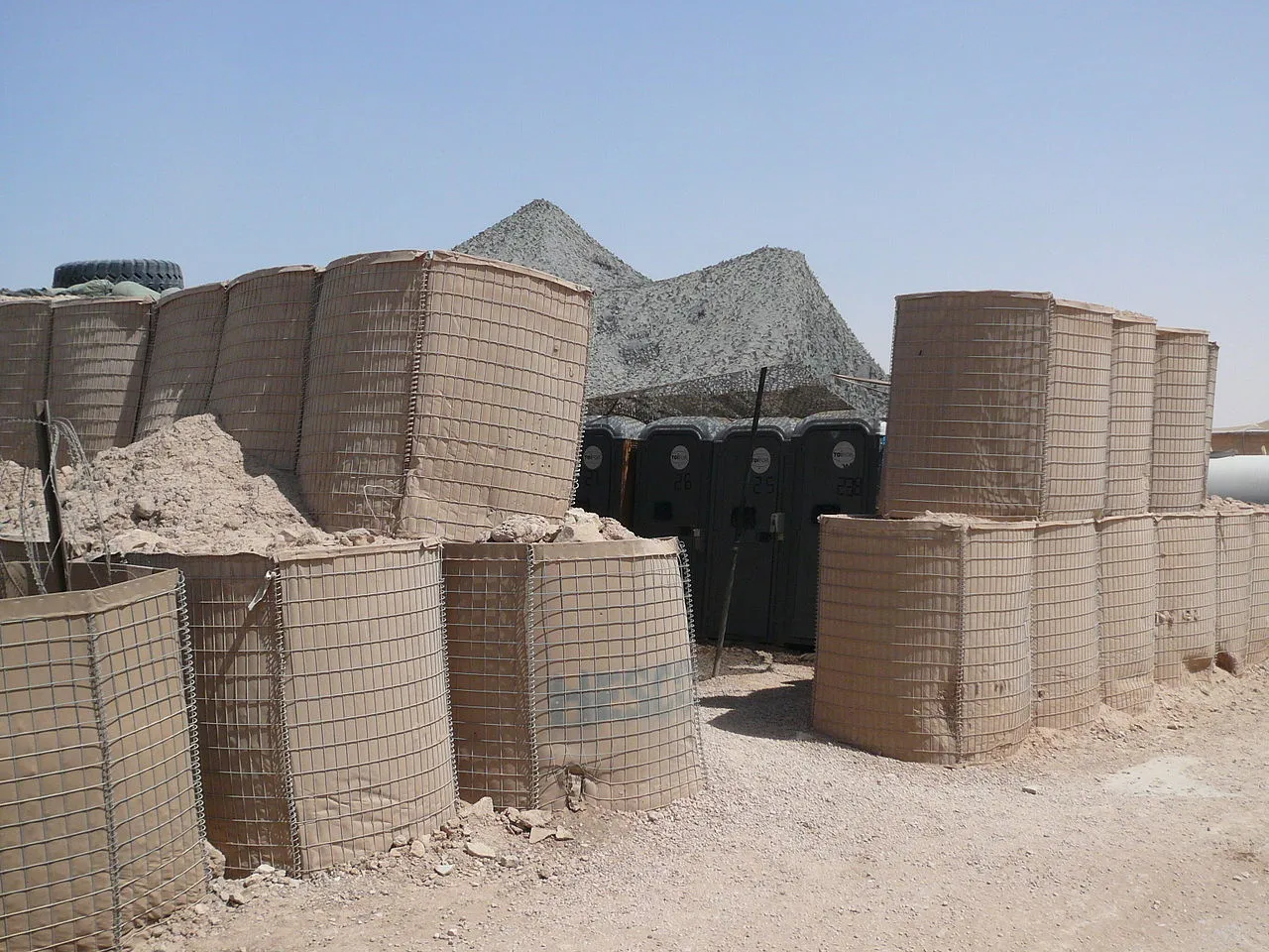 A Hesco Bastion wall protecting portable toilets