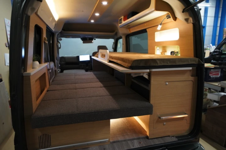The Oka Miniature Cruise Cozy has a unique bunk bed layout that uses the kitchen as a sleeping platform