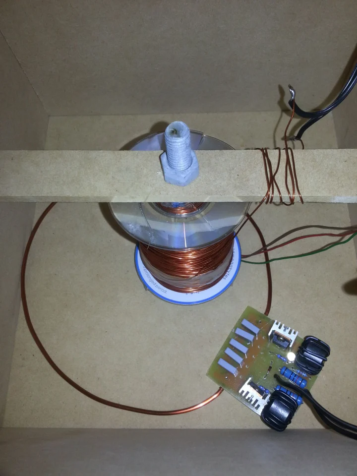 Hidden inside the box: a single wire ring connected to a power supply for the wireless transfer of power and a huge electromagnetic drive coil for levitating the LED light module underneath