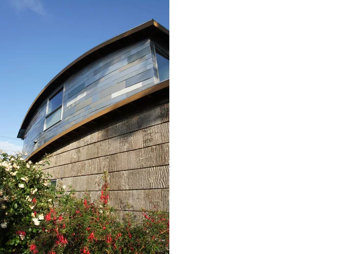 The car scraps were cut into long tile-like shapes and used to complete the upper outside walls of the house, rendering a similar appearance to slate