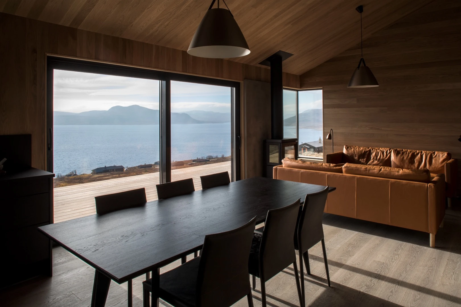 Inside, the cabin is arranged around an open living area with a living room, kitchen, and dining area