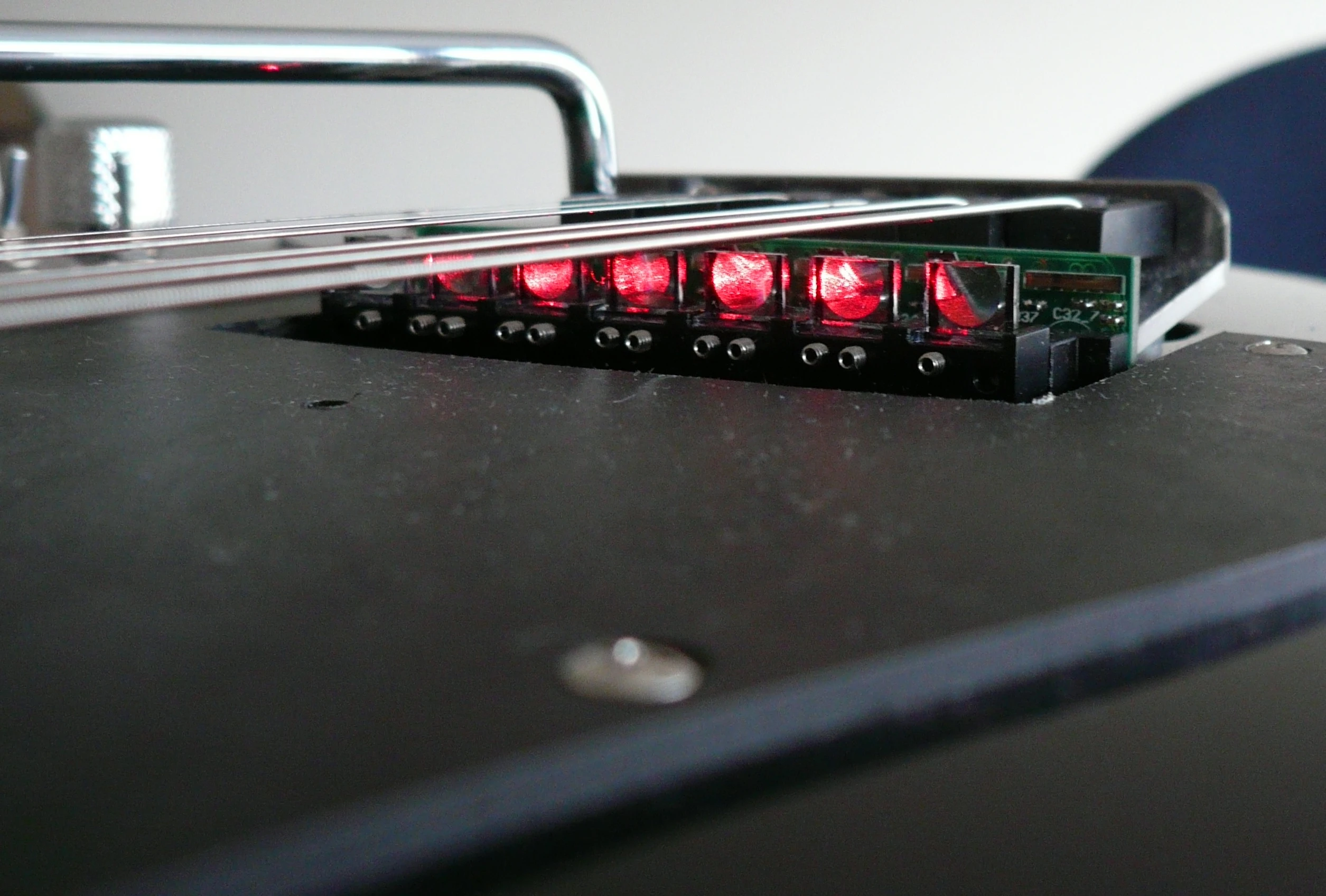 At the bridge end of the guitar, each string of the guitar has a laser diode sat underneath it that sends out a beam parallel to each string towards the end of the fingerboard