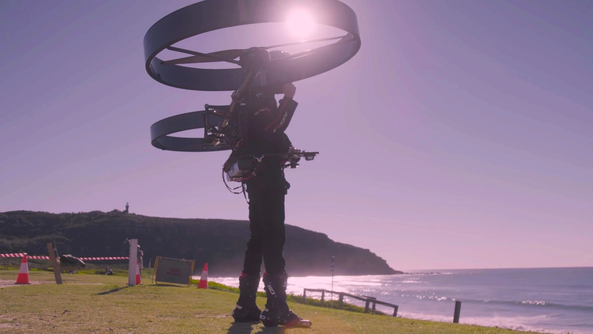 Large rotating tubes hold the rotors to the rigid backpack, and the batteries appear to be slung at the bottom of the frame