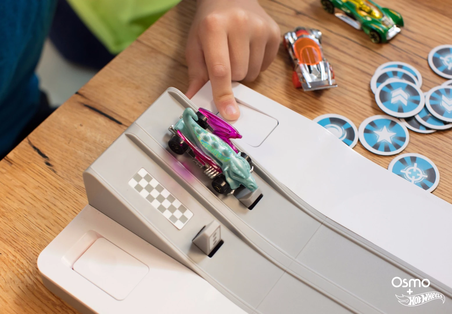 To start the race, players pick a car, place it on the ramp, and press the button to launch it into the digital world