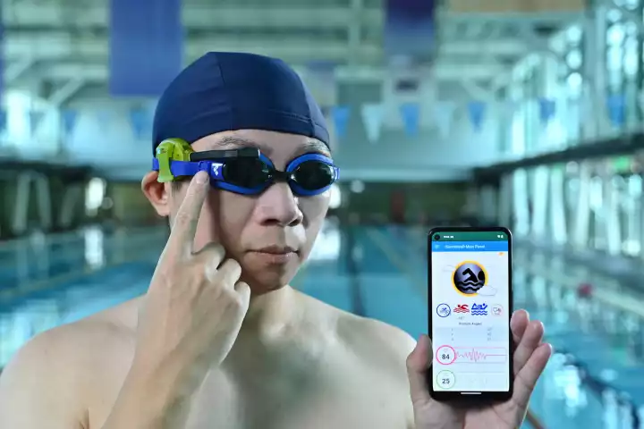 iSwimWeaR (green device with black arm) works with existing goggles or masks, along with a smartphone app