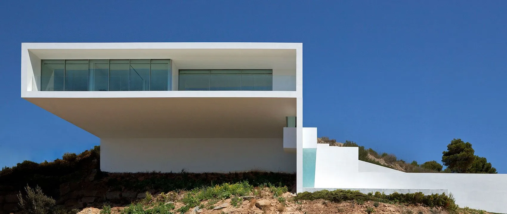 Another impressive cantilevered structure, this white modernist masterpiece from Fran Silvestre Arquitectos is on the coast of Spain facing the Balearic Sea. The clean white concrete building juxtaposes against the craggy grey landscape