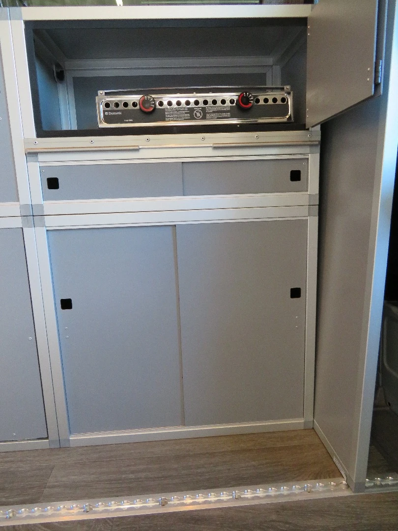 The slim kitchen area uses a portable stove in place of a built-in cooktop