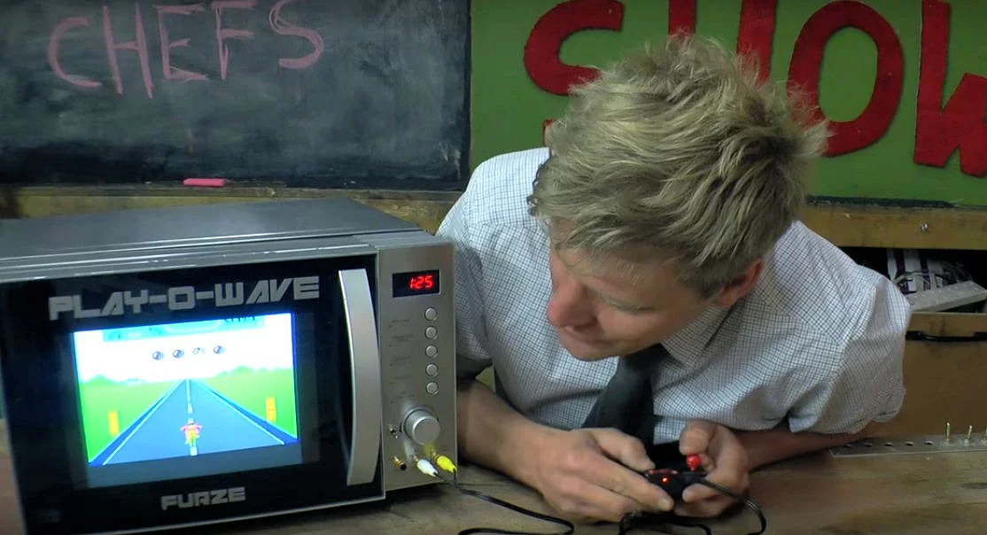 Colin Furze plays an old school video game while waiting for his meal to cook
