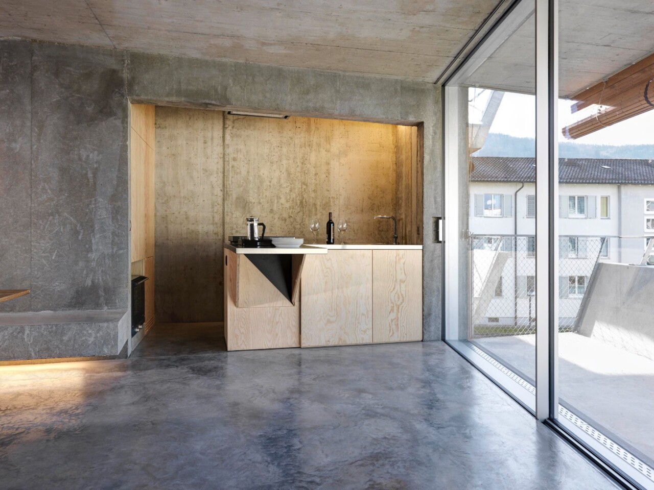 Wooden cabinetry and doors contrast with all the concrete in Affordable Housing Langgrütstrasse