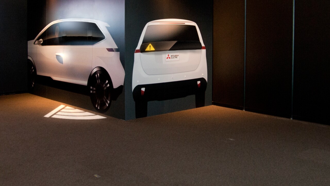 Mitsubishi's security lighting system projects a triangular Wi-Fi-like symbol onto the road beside the car when a door is about to open