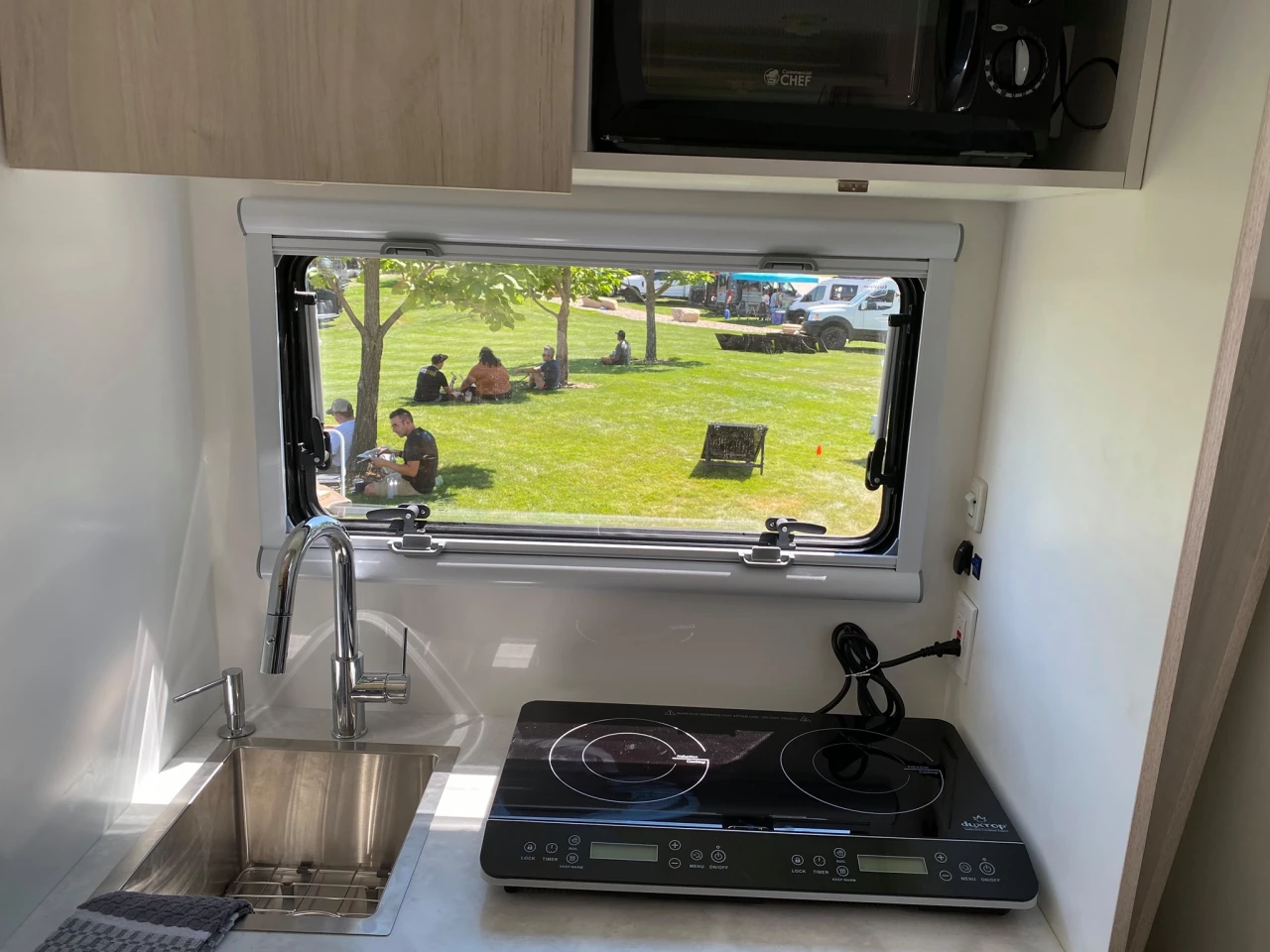 The kitchen uses a portable indoor/outdoor induction cooktop for flexibility; a single-burner is standard, dual-burner optional