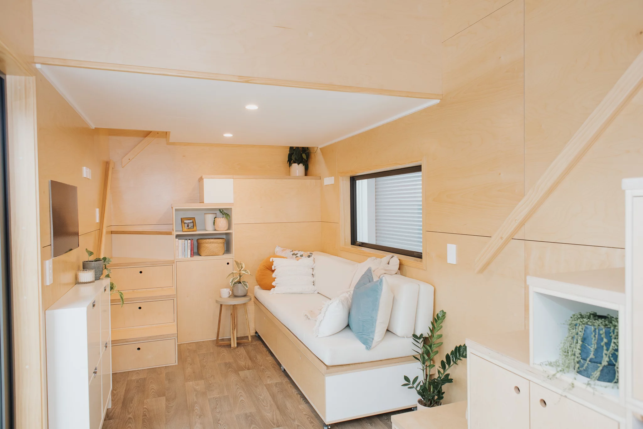 Visitors enter the Kererū Tiny House into the living room, which is finished in plywood