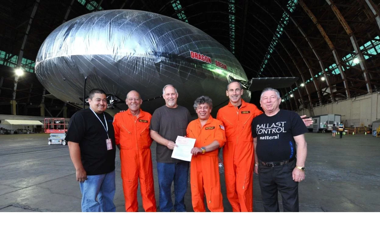 Pictured (L-R) Alex Canto, Director of Quality Control; Corky Belanger,Sr., Test Pilot; Kurt Krumlauf, Sr. Aviation Safety Inspector for the FAA, Igor Pasternak, CEO/Flight Engineer, General Raymond Johns, Test Pilot; and Anatoliy Pasternak, VP of Production with the FAA airworthiness certificate for the Aeroscraft (Photo: Aeros)