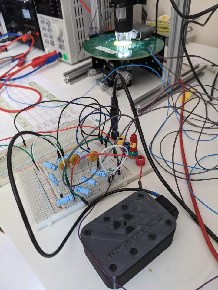 Arkenlight's early stage tritium beta-battery, in the black box, powers an Axorus artificial neuron, in the circle of light, in a proof-of-concept both companies hope will lead to a medical-grade implant