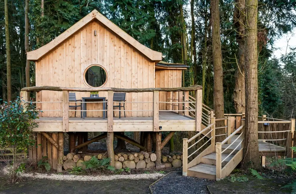 The Bird house in Somerset, England, a solar-powered treehouse-style dwelling supported by sections of tree trunk stilts and accessed via wooden steps