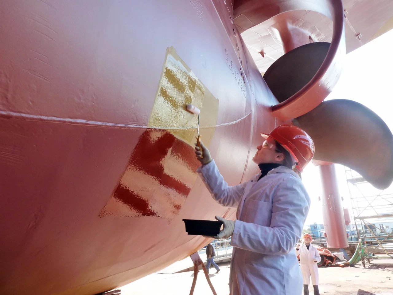 Dr. Martina Baum applies a test patch of the paint to the ship "African Forest"