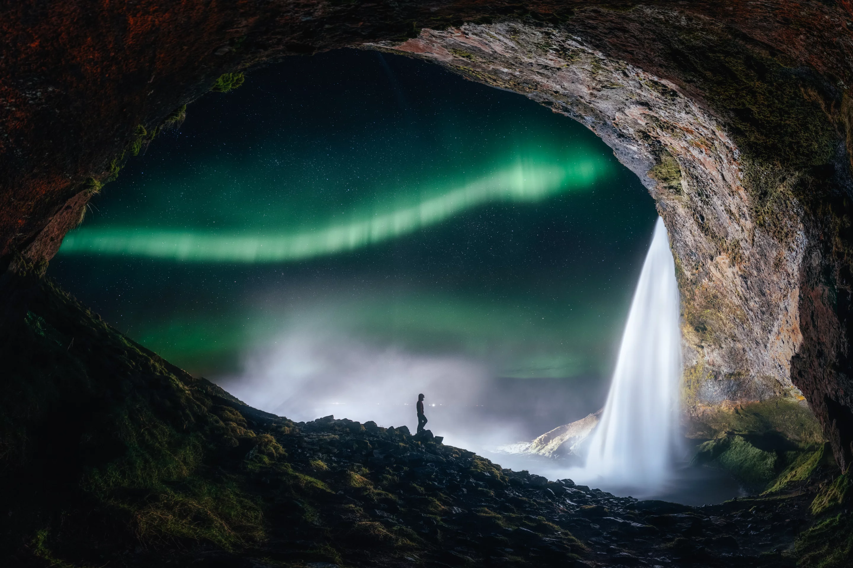 The small cavern perfectly frames a mesmerizing view of the aurora flaring up, the shining stars and the magnificent Seljalandsfoss waterfall situated on the South Coast of Iceland with a drop of 60 meters. The photographer stood there thinking about this view and how our universe is just a small part of a much greater space.Seljalandsfoss, Iceland, 8 January 2019