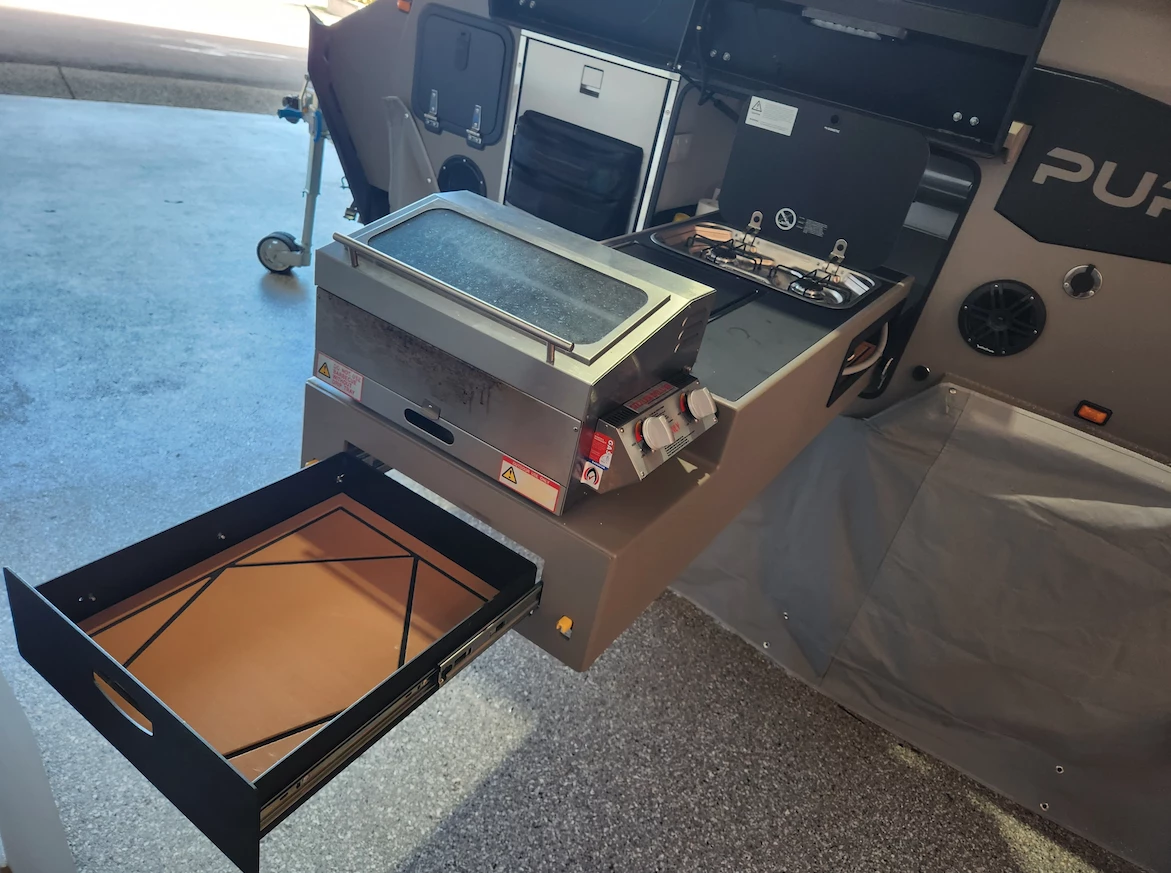 The slide-out kitchen with stove, sink, grill and recessed cutting board comes standard