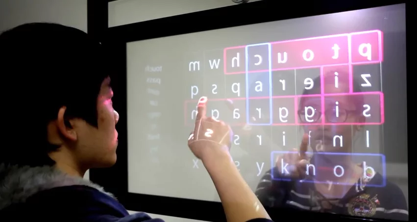 When users on either side touch the plexiglass, the location and movements of their fingertip are detected by the infra-red touch sensor frame on that side