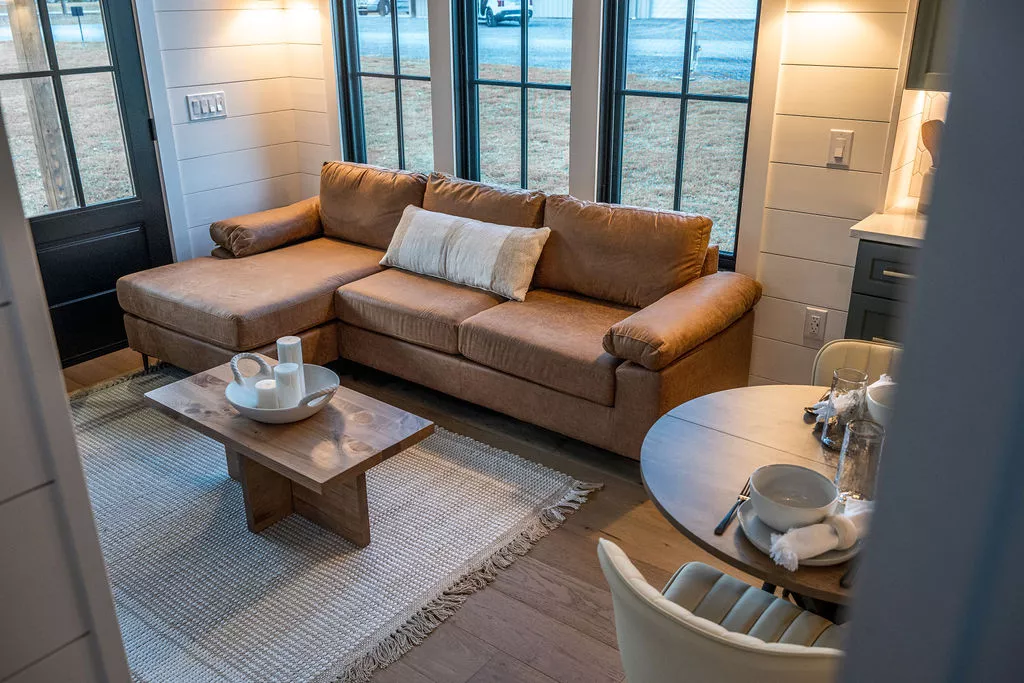 The Hidden Mountain Tiny Villa's porch opens onto the living room, which includes an L-shaped sofa and an entertainment center