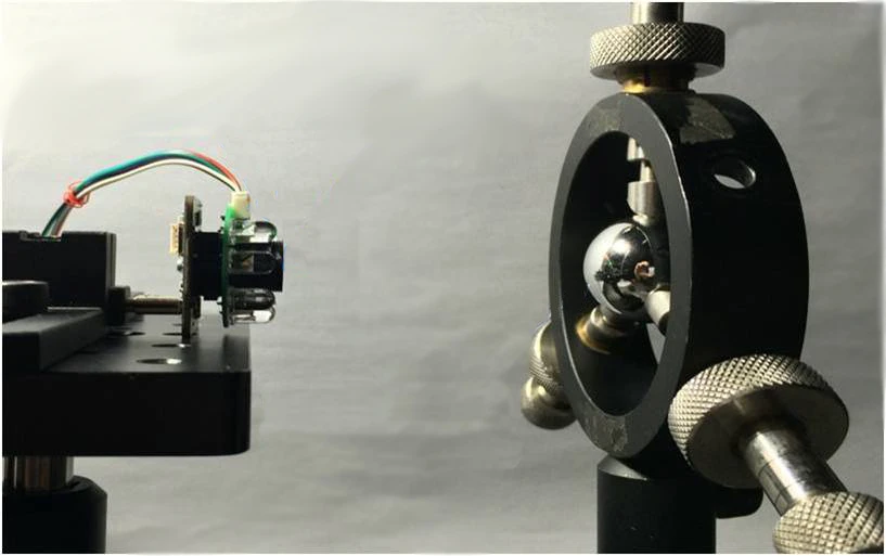 A pupillometer testing setup, with the device on the left and an eye model on the right