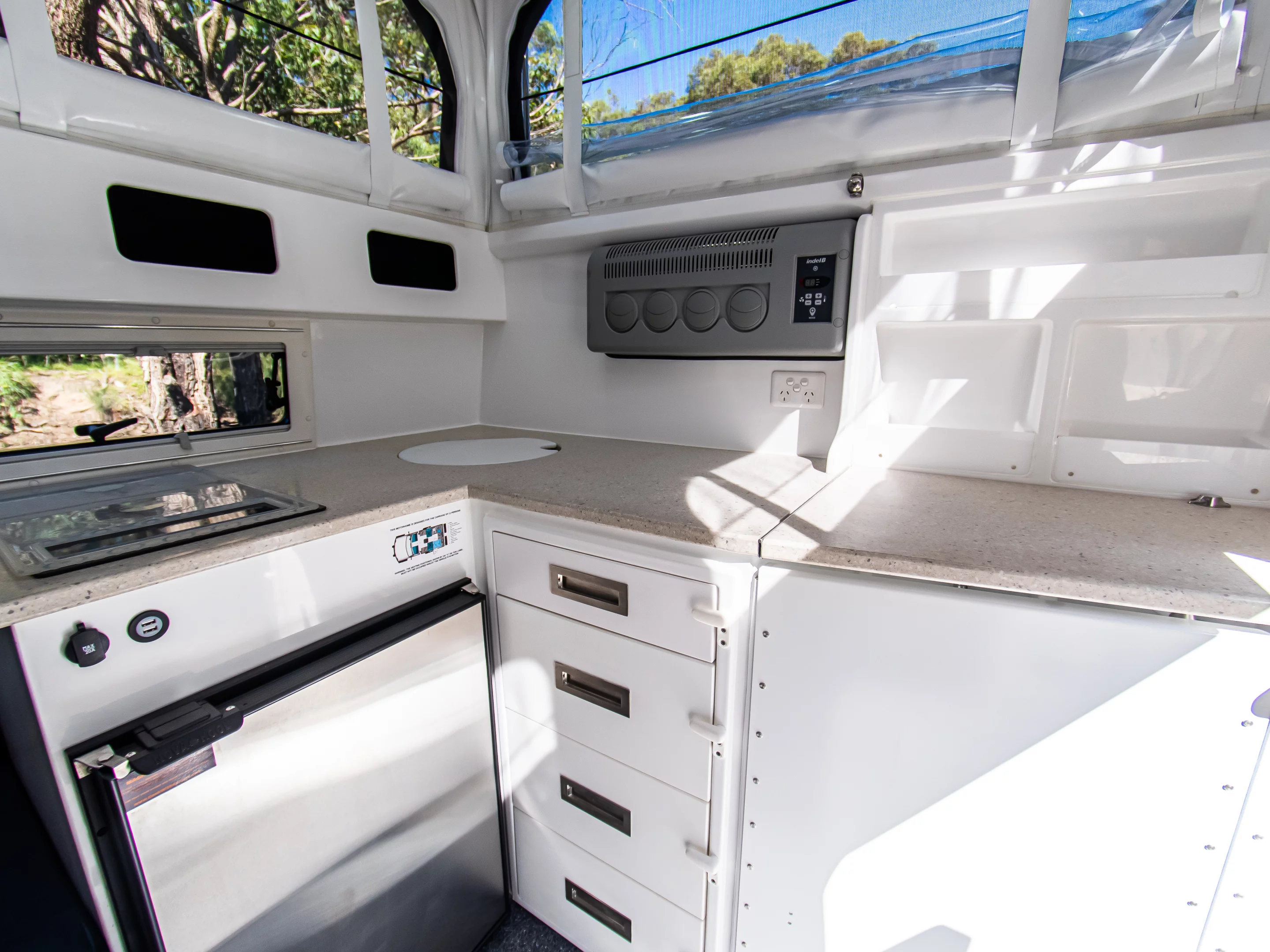 The corner kitchen comes fully equipped with an induction cooktop, sink, fridge/freezer, drawers and countertop