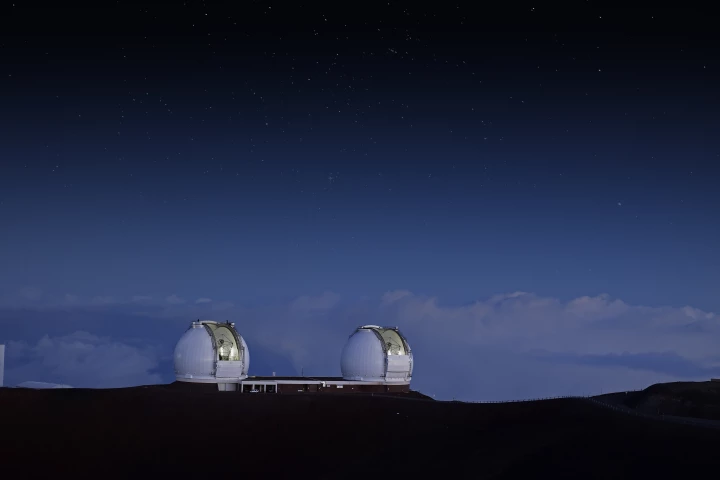 Two telescope domes on a hill at sunset