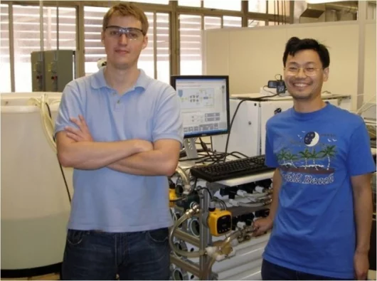 Graduate students John Thompson (left) and Aihua (Richard) Zhu standing in front of the M3 water filtration and desalination system (Photo: UCLA Newsroom)