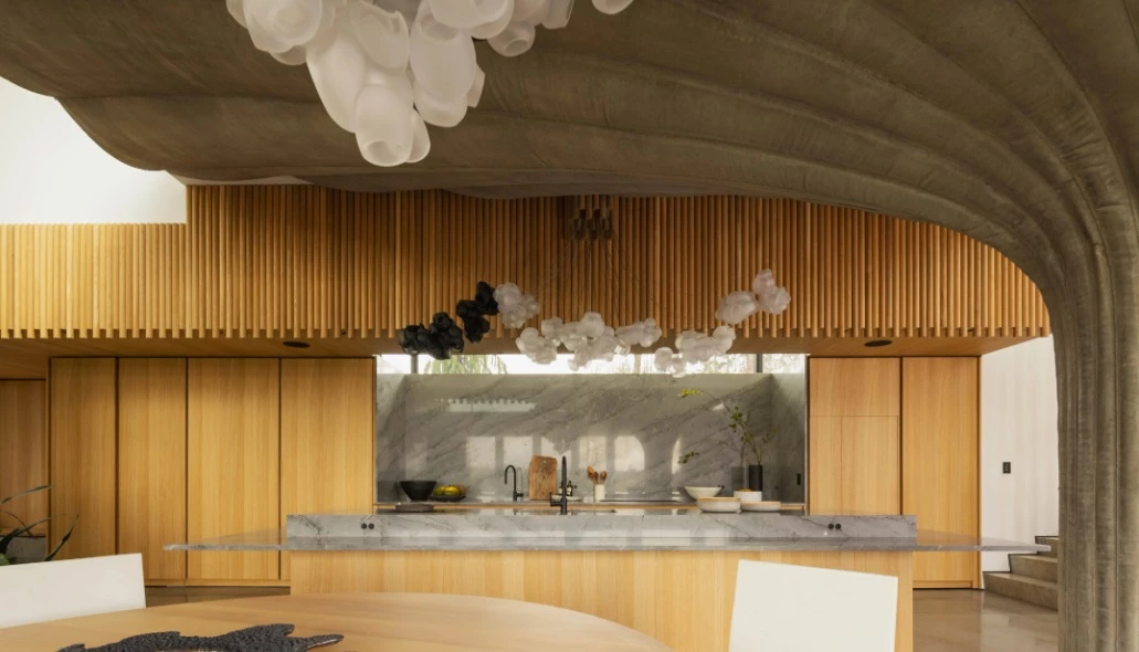The large open modern kitchen is draped by a trumpet column