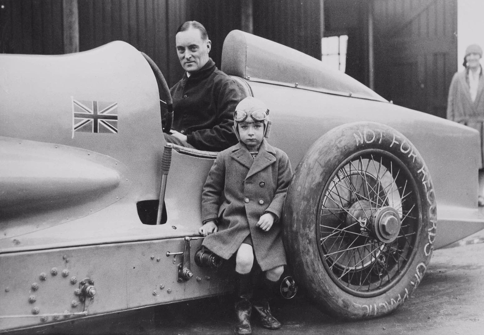 Sir Malcolm Campbell in the Blue Bird, with a young fan standing alongside