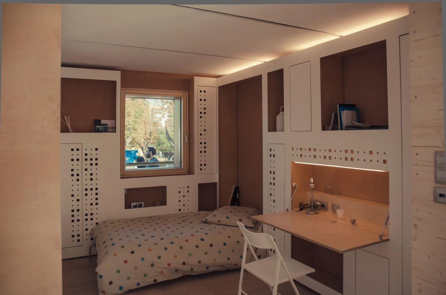 A storage wall cleverly disguises and stores a series of portable furniture elements that can be transformed into a bed, table or office