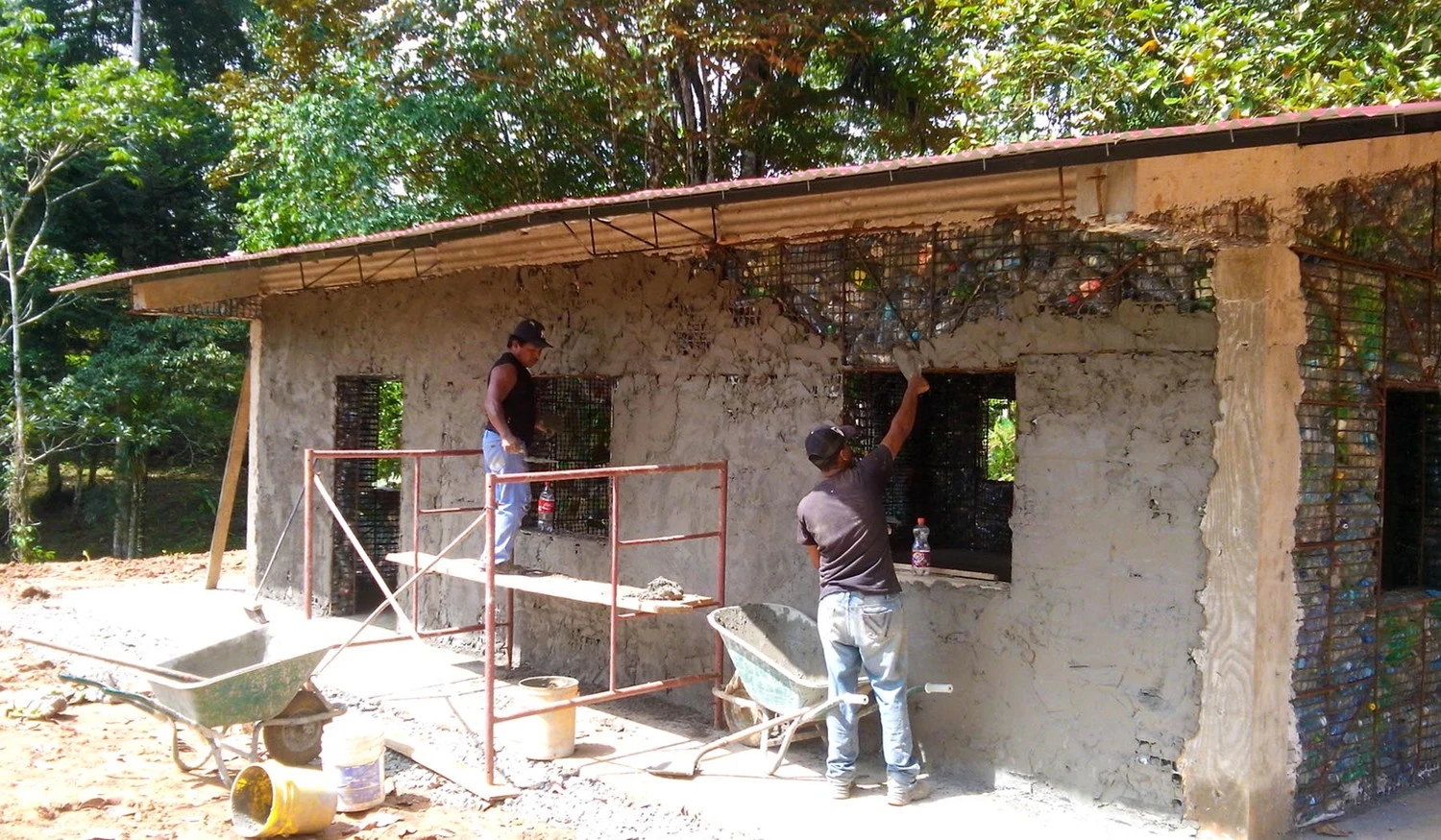 The plastic bottle and steel mesh structure is then covered with concrete, with roofs, plumbing, septic tanks, and electricity, etc, added later