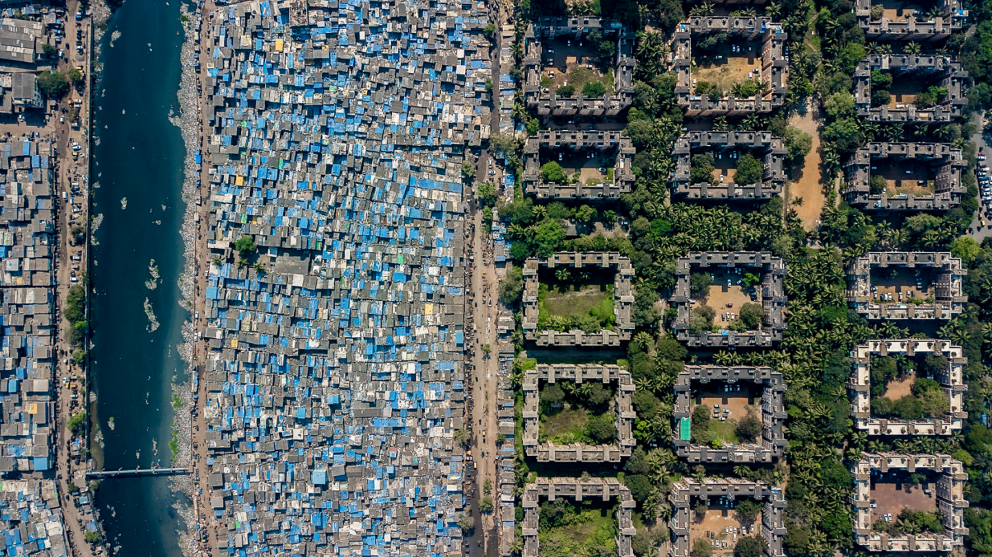 Very tightly packed homes make up this slum in Mumbai, India, alongside greener pastures