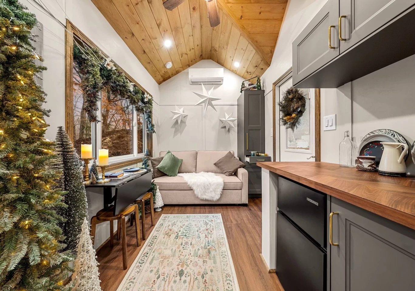 The Spruce is entered into its living room, which includes a sofa bed and some storage