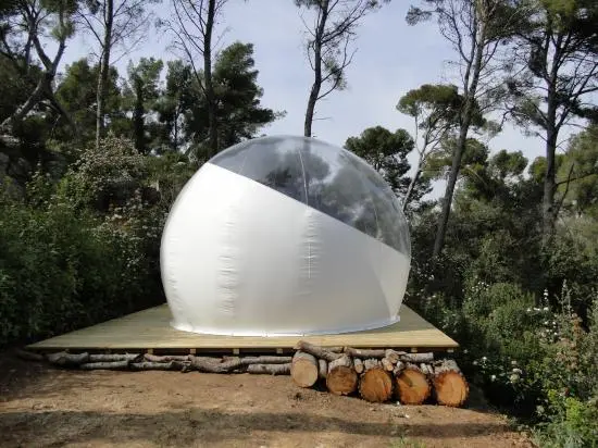 Each bubble is set up in a forested area on a flat, rigid floor near a wooden outhouse
