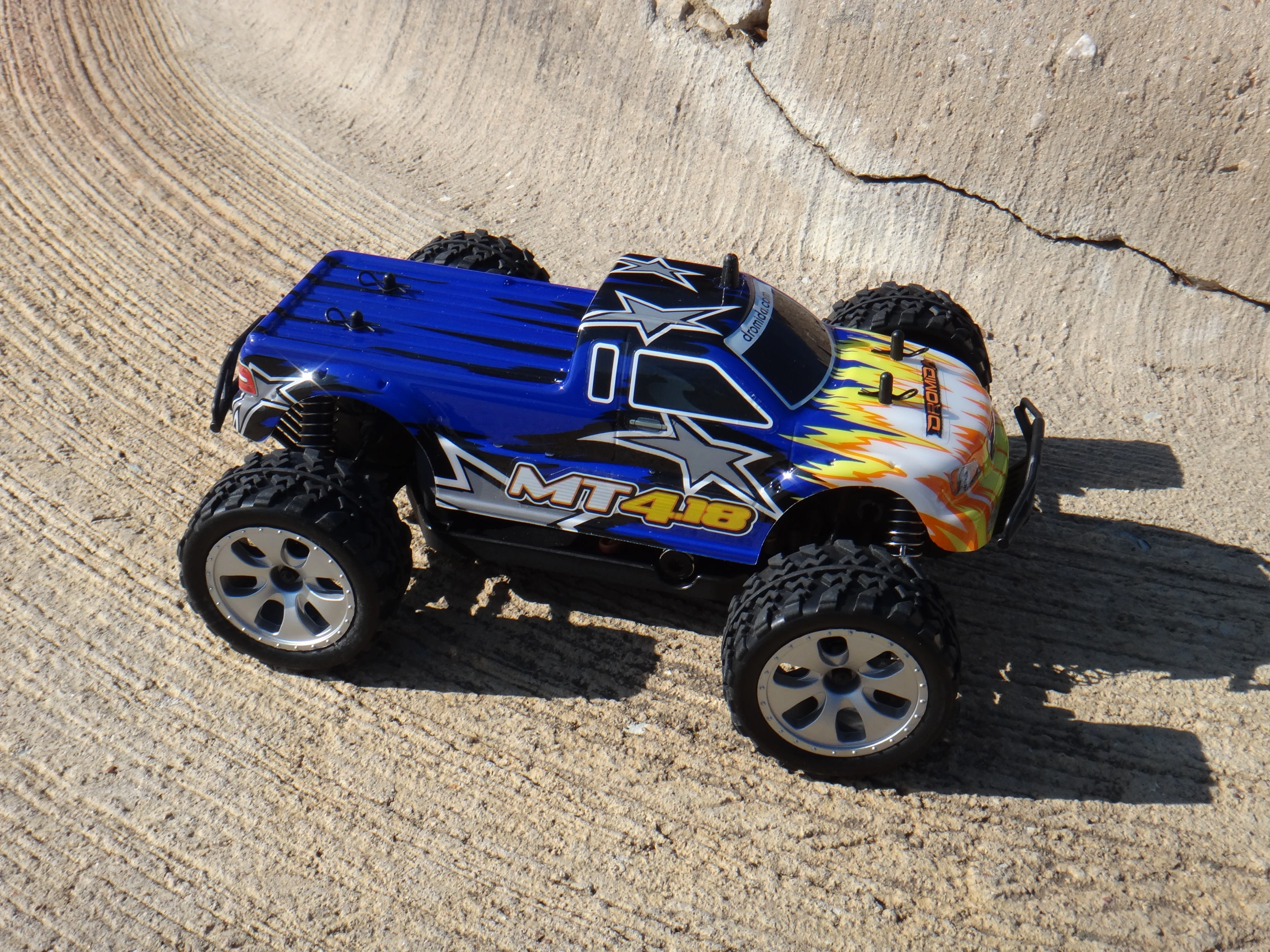 The monster truck's larger wheels are more adept at covering rougher terrain, and its narrow body helps it roll back onto its wheels after a bad tumble