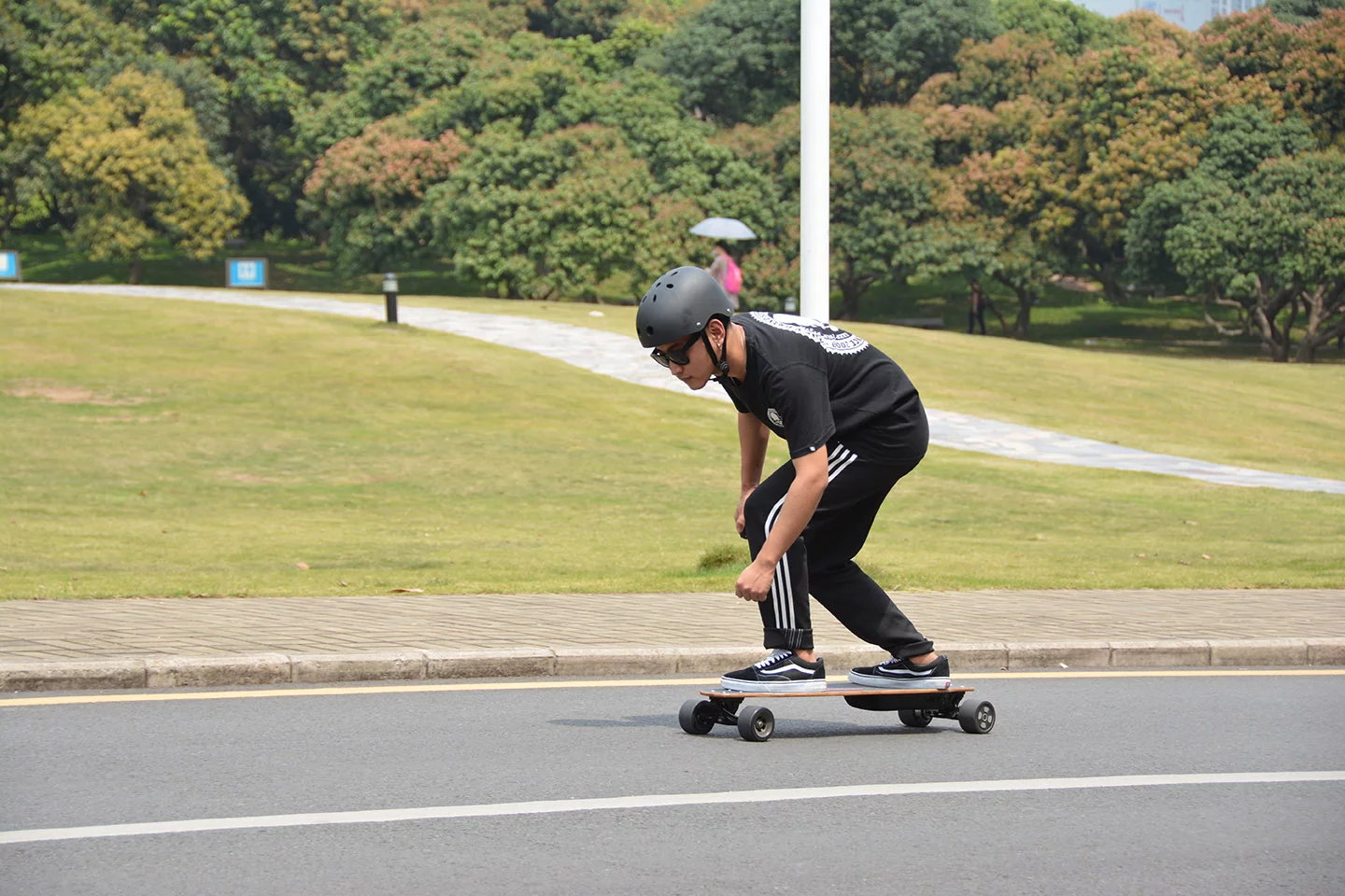 The Pomelo Pro electric longboard rider controls the speed and braking using a wireless hand remote