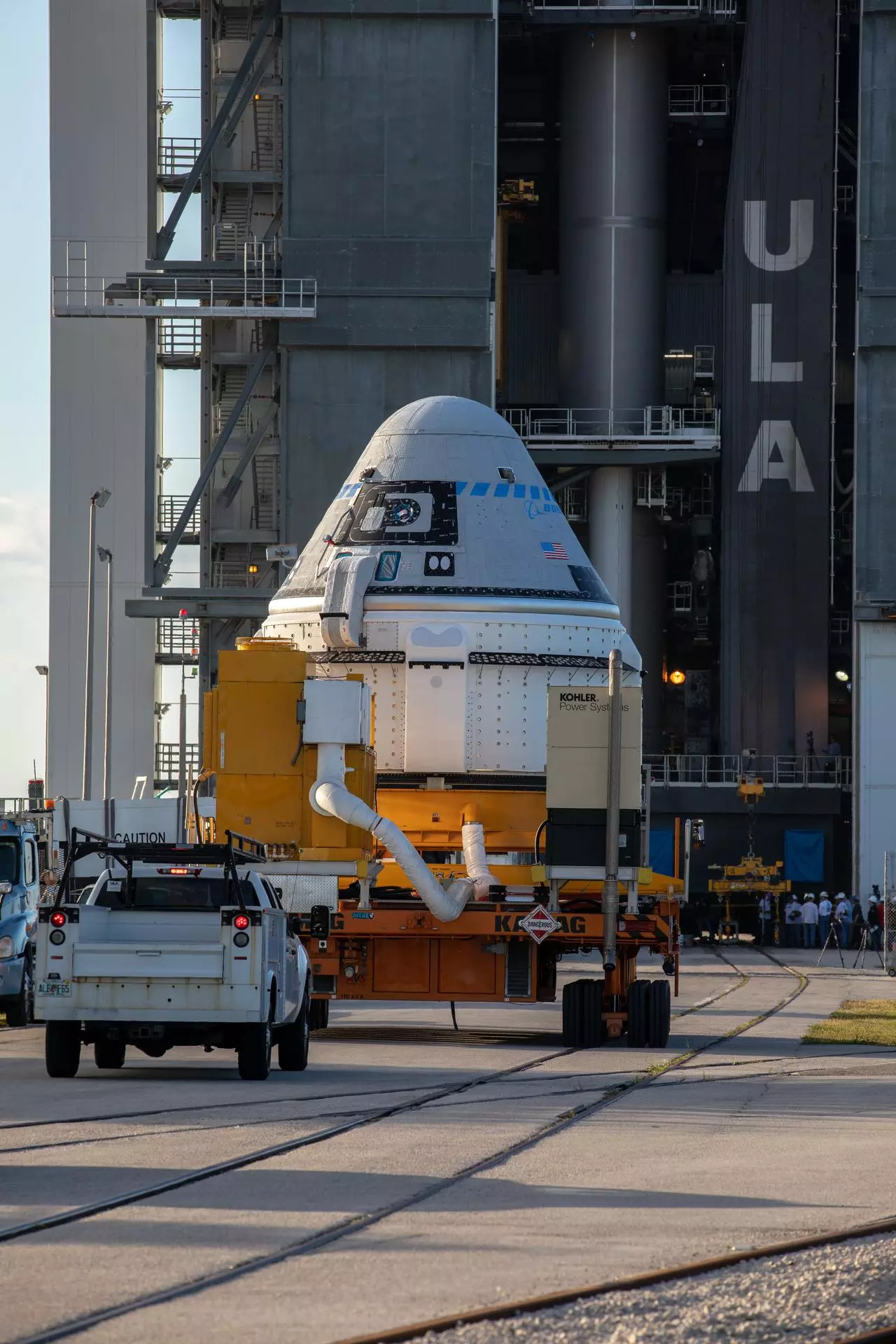 A transporter carrying the Boeing CST-100 Starliner spacecraft arrives at the Vertical Integration Facility