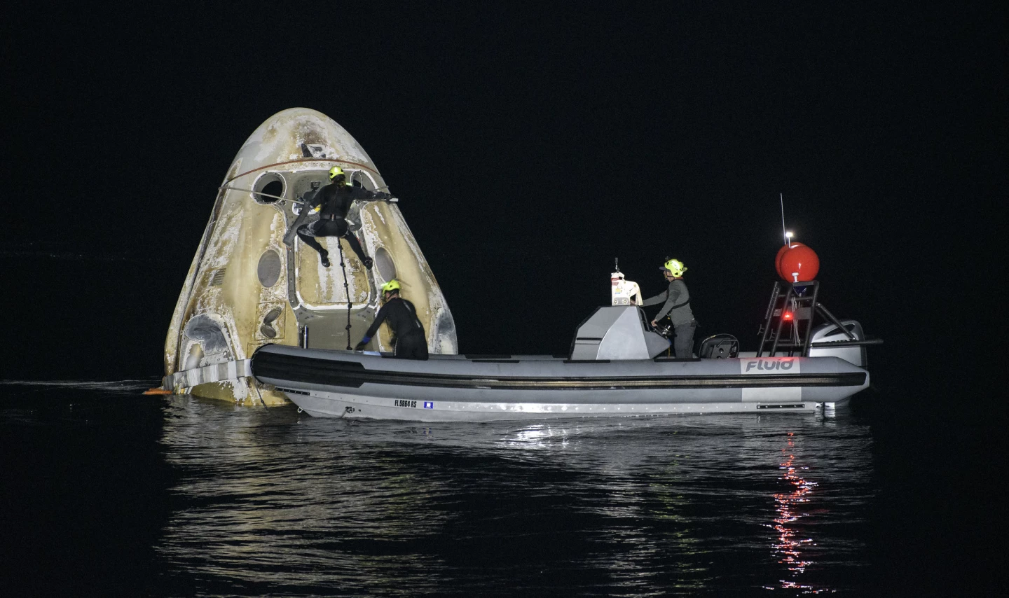 A recovery crew tends to the Crew Dragon capsule shortly after splashdown