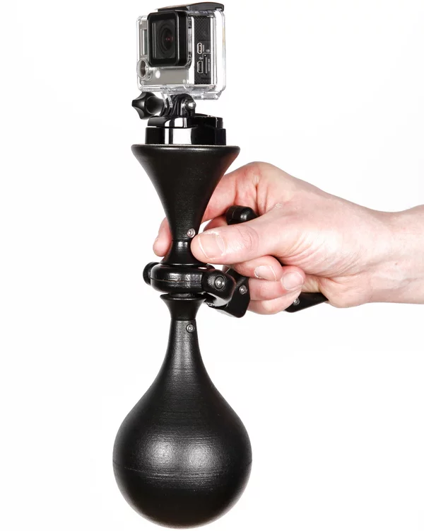 The steel, aluminum and nylon device is held by its gimbaled handle in one hand, with the forefinger and thumb used to pan and tilt